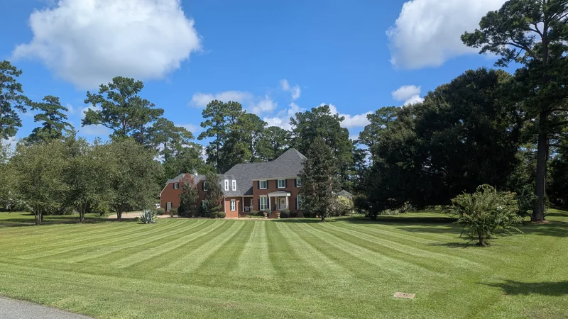 Freshly mowed lawn at a brick home and tree-lined property